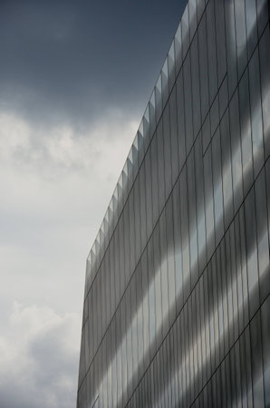 Geometric office block with dark cloudの写真素材