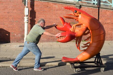 BRIGHTON SUSSEX  UK 29 September  2015: Man pushing lifesize plastic lobsterのeditorial素材