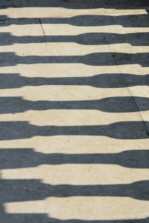 Shadows of pillar on concrete pathの写真素材