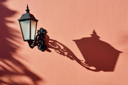 Antique lamp with shadow and pink wallの写真素材