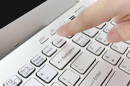 Finger pushing delete button on laptop keyboard