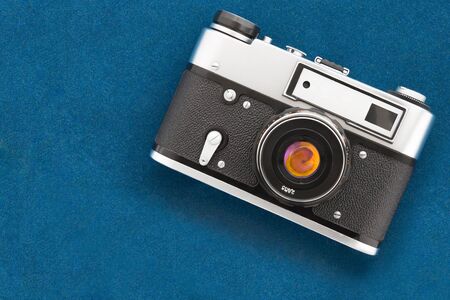 Vintage old-fashioned photo camera lying down on velvet blank background. Top view.の写真素材