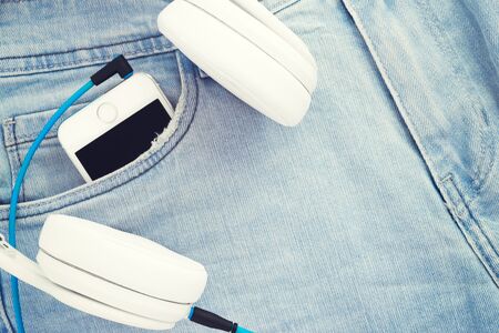 White headphones and smartphone in the pocket of jeans. Listen to music everywhereの写真素材