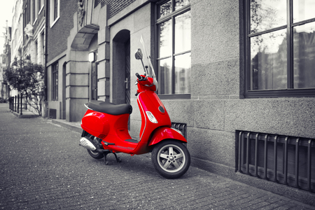 Red vintage scooter parked on sidewalk of empty city street. Selective color effectのeditorial素材