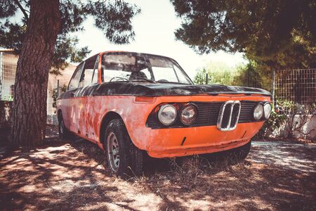 Old abandoned vintage car rusting under the tree. Vintage filterのeditorial素材
