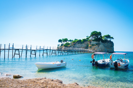 Amazing seascape with azure sea water and wooden bridge leading to the exotic island. Lifeboats picturesquely moored to the beach. Summer vibes. Summer vacation travel backgroundのeditorial素材