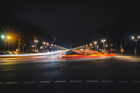 Long city street with light trails at night. Long exposure photo of straight wide road in Berlin