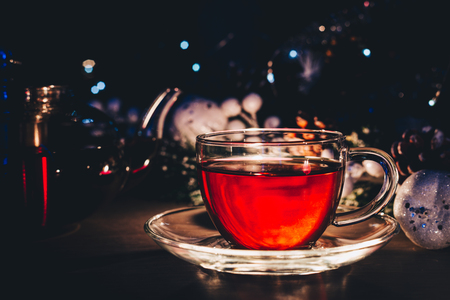 Cup of tea in a dark room near christmas tree with lightsの写真素材