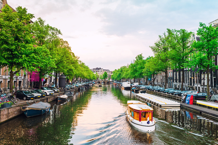 Channel in Amsterdam at sunset. Boat going down the river in Amsterdam. Picturesque cityscape of Amsterdam streets.の写真素材