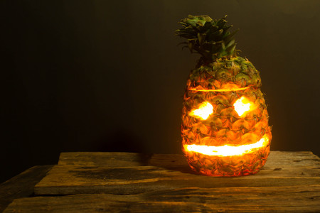 Pineapple Halloween jack lantern placed on the wooden floor and black backdrop.の写真素材
