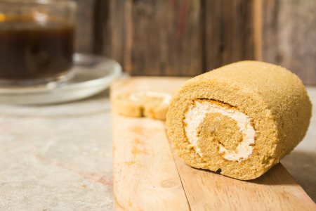 Roll cake small smell the coffee, put on a wooden background old wooden brown and black coffee, perfect for breakfast and coffee breaks.の写真素材