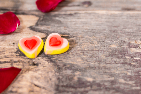 Tasty Jelly  candies shaped heart with red Rose petals, perfect to give as. Gifts on Valentine's day, wooden background.の写真素材