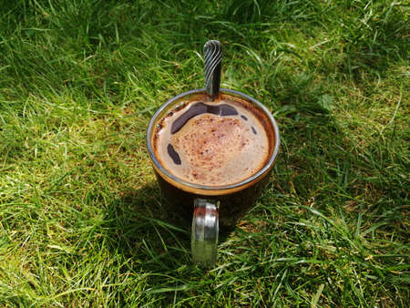 A cup of coffee on the grass in the garden. Selective focus.の写真素材