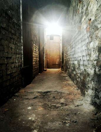 Abandoned corridor in the dark with light coming through the doorの写真素材