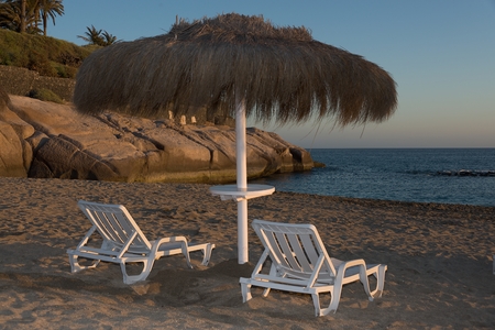 Two wooden dack chairs and umbrellaの写真素材