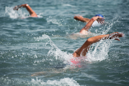 Group of swimmers swim in the sea at the races in triathlonの写真素材
