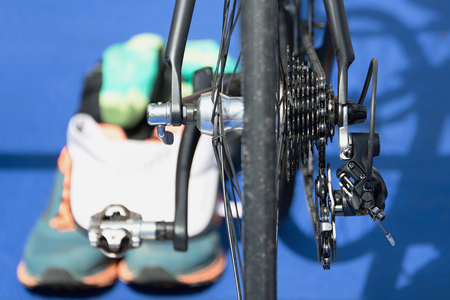 Triathlon bike the transition zone,detail detail bicycle derailleur.In the background running shoes