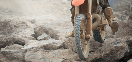 Racer on a race bike during a competition at enduro,ride over rocks