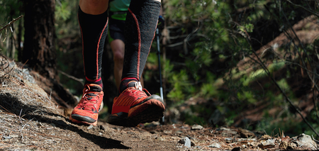 Trail running workout outdoors on rocky terrain, sports shoes detail on a challenging forest track