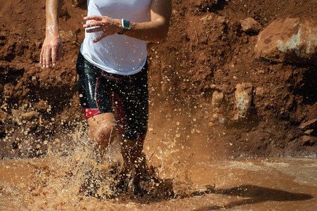Trail running man in the muddy terrainの写真素材