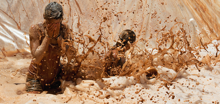 Mud race runners, jump into dirty water with foamの写真素材