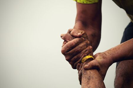 Mud race runners.Couple hold hands,help when overcoming hindrances mudの写真素材