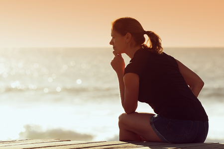 Silhouette of woman sitting at thought of some things with hopeの写真素材