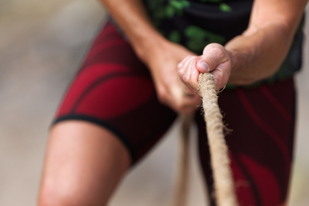 Tug of war male hands holding a ropeの写真素材