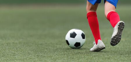 Foot of a child football player and ball on the football fieldの販売画像