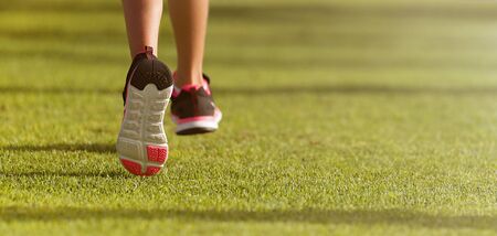 Running children detail on sport shoes running along green grass