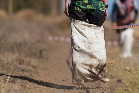 Mud race runners, playing potato sack jumping race