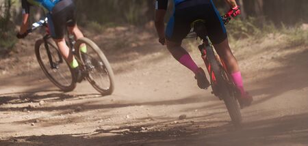 Athletes mountain biking on forest trail, mountain bike raceの写真素材