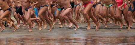 Triathlon athletes ready to startline, racing in swimming, running into the seaの写真素材