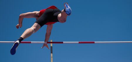 Competition pole vault jumper male on blue sky background