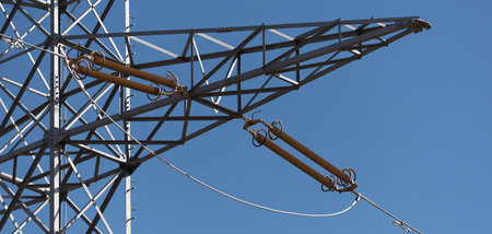 The power pole high voltage lines aginst blue sky