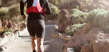 Male athlete run mountain race wth hydratation trail vest for running