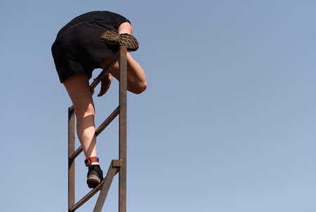 Participant in extreme obstacle race climbing over hurdleの写真素材
