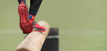 The feet of an athlete as she's walking on a wooden beam outside in the parkの写真素材