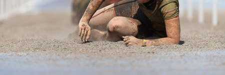 Mud race runners. Crawling, passing under a wire obstacles during extreme obstacle race
