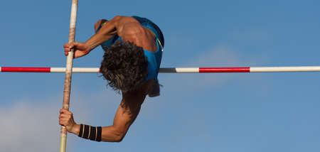 Competition pole vault jumper male on blue sky background