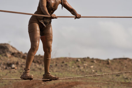 Mud race runners, overcoming an obstacle on a steel ropeの写真素材