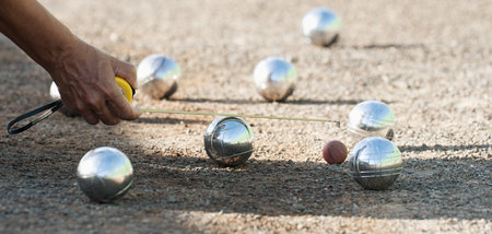 Petanque game, woman measuring the distance of petanque ball in petanque field, deciding who's the winnerの写真素材