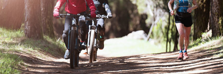 Cycling and mountain biking trails, sports activities in the forest, cycling, running. Older mens cycling. Older woman on training runの写真素材