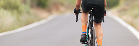 Male cyclist riding racing bicycle, man cycling on countryside summer road. Training for triathlon or cycling competitionの写真素材