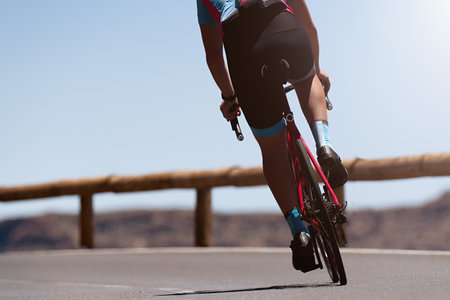 Male cyclist riding racing bicycle, man cycling on countryside summer road. Training for triathlon or cycling competitionの写真素材