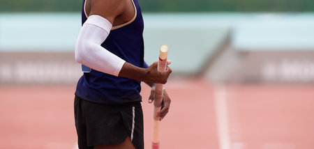 Pole vaulter prepares for jump, looking from behindの写真素材