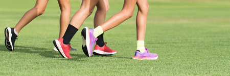 Three female athletes runners, athletes feet running on grass. Female and male fitness sunlight jogging workout. Sport athlete active lifestyle concept. Athletic of legs runningの写真素材