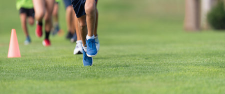 Running children, young athletes run in a kids run race, running on grass detail on legs, running in the light of morningの写真素材