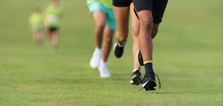 Running children, young athletes run in a kids run race, running on grass detail on legs, running in the light of morningの写真素材