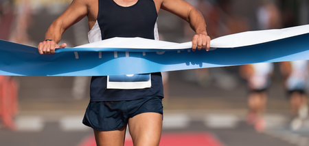 Man running towards the finish line, male runner wins the outdoor race in the city. Passes finish line as a winnerの写真素材